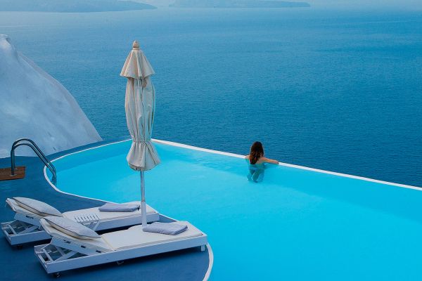 Woman relaxing in an infinity pool looking out at the ocean