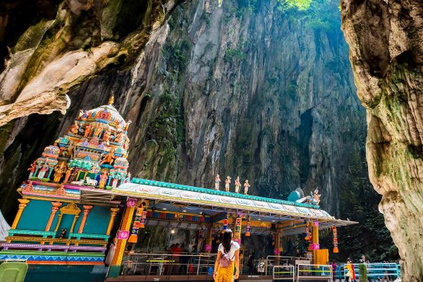 Lady surrounded by a cave with small boat in the background