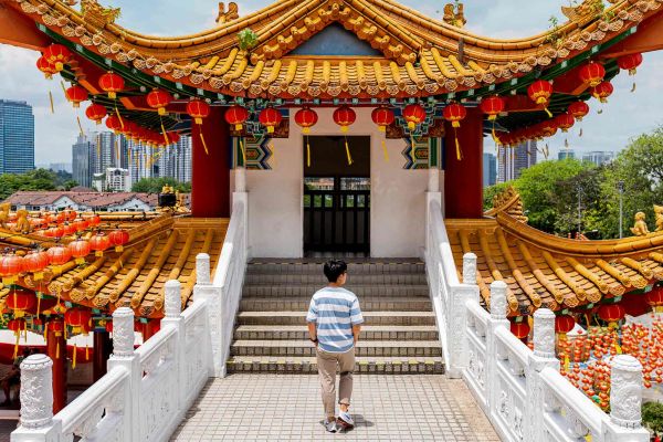 Woman standing beneath Kek Lok Si Temple in Malaysia, with hundreds of red and yellow hanging lanterns
