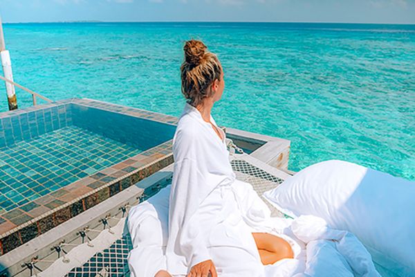 Woman in white relaxing next to an infinity pool by the ocean