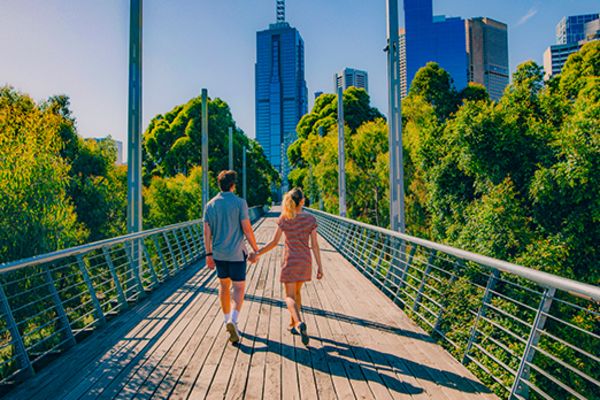 Couple walking hand in hand on a narrow bridge in Melbourne