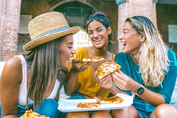 Three friends smiling, sharing pizza