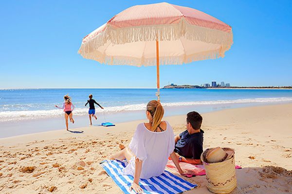 Couple lying on a beach watching their two children run to the water