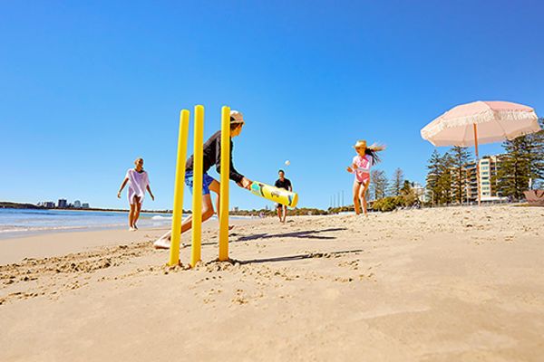 People playing beach cricket on a sunny day