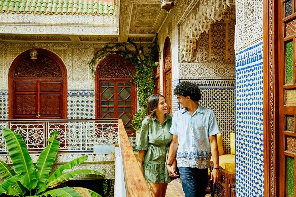 Couple smiling at each other walking along a tight balcony in Morocco