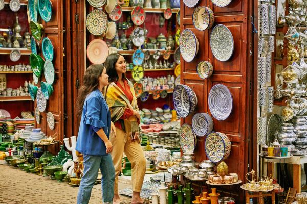 Two women looking at hundreds of colourful bowls and plates at a marketstall