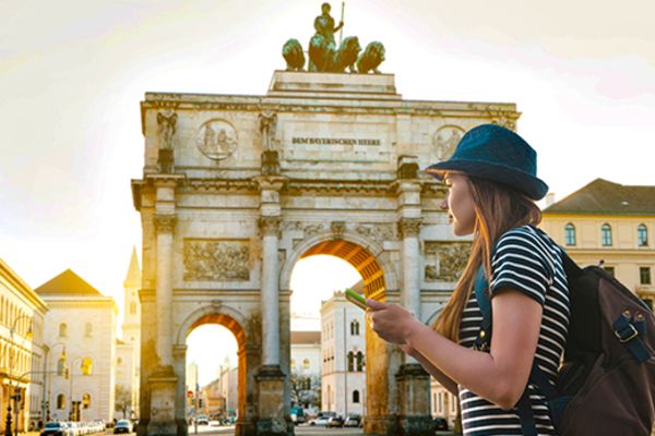 Woman looking at her phone with Siegestor arch in Munch in the background