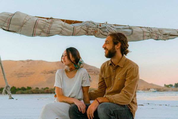 Couple sitting on edge of smaller boat along the Nile River
