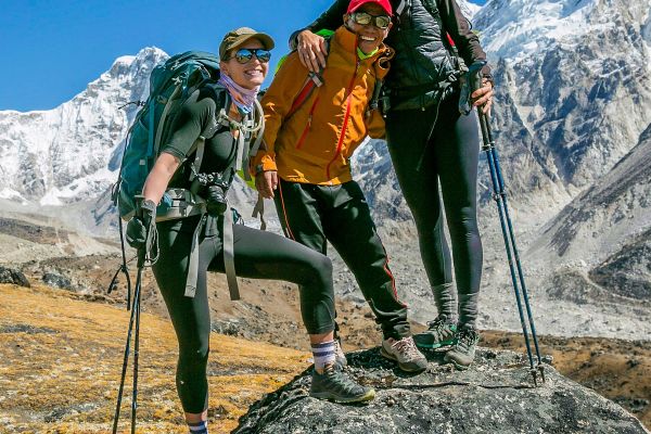 Three hikers posing in front of tall snow-covered mountains