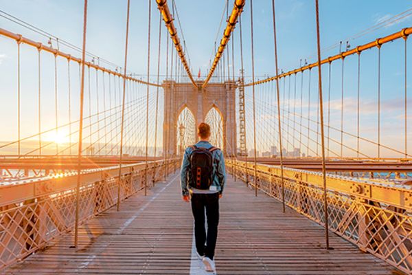 Back shot of a man crossing the Brooklyn Bridge