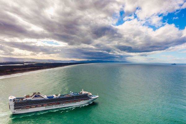 Couple riding bikes through grassy fields with snow-covered mountains in the background