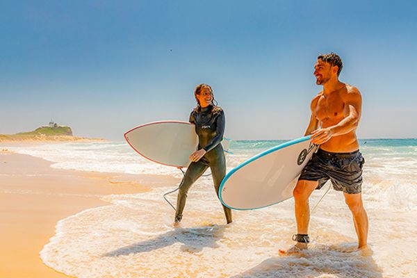 Two surfers carrying surfboards walking out of the surf
