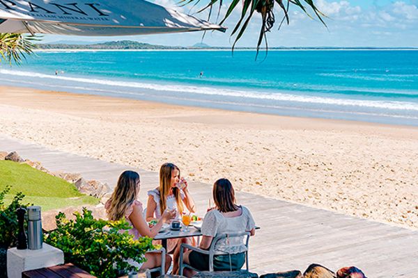Three women eating brunch next to a beach