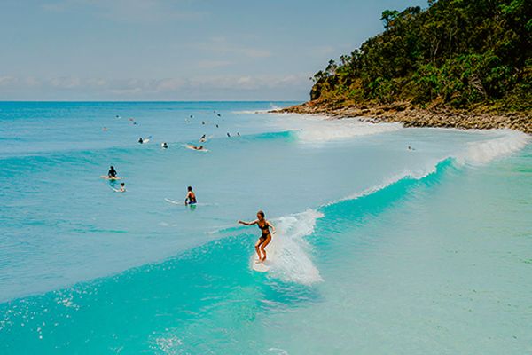 Surfers and swimmers in high saves on a beach in Noosa
