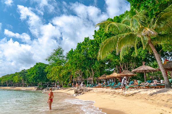 Wide shot of a woman standing in the surf on a tropical beach