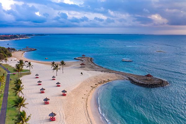 Wide shot of a beach lined with beach umbrellas at sunset