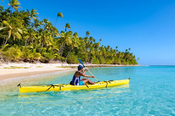 Man in a yellow kayak rowing into the ocean
