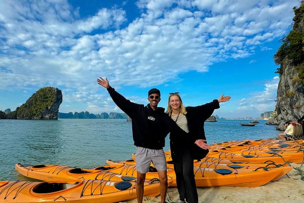 Two people standing in front of kayaks
