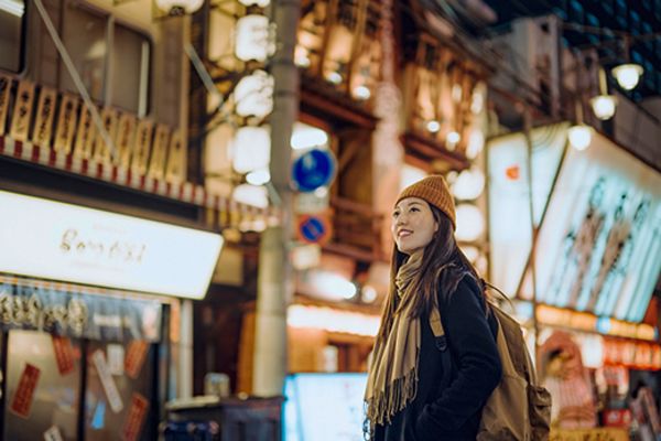 Woman in warm clothing in a neon-lit street in Dotonbori, Osaka