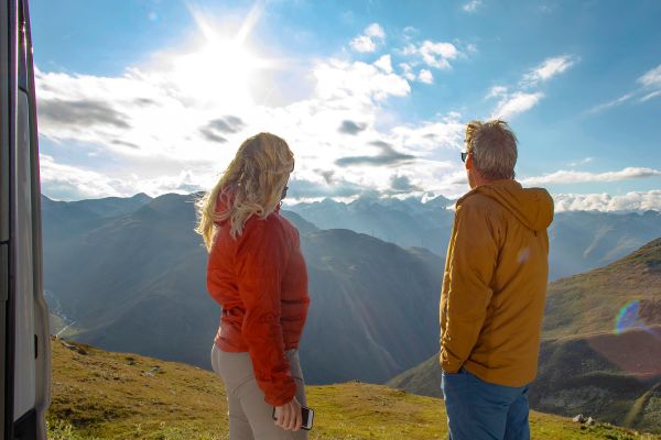 Elderly couple atop a hill looking out at a sunrise