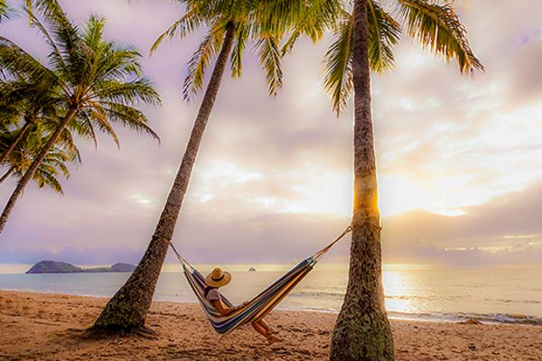 Woman in a hammock on a beach at sunset