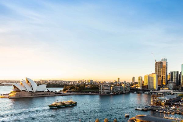 Drone shot of smaller cruise ship in front of Sydney Opera House