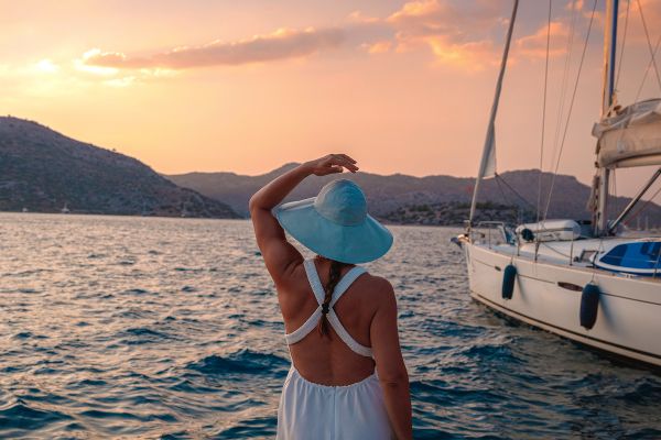 Woman in a white dress on a sailboat looking out at the ocean