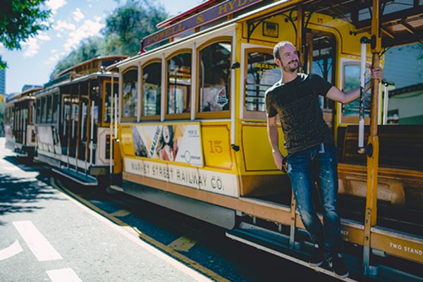 man holding onto rail of tram in san francisco