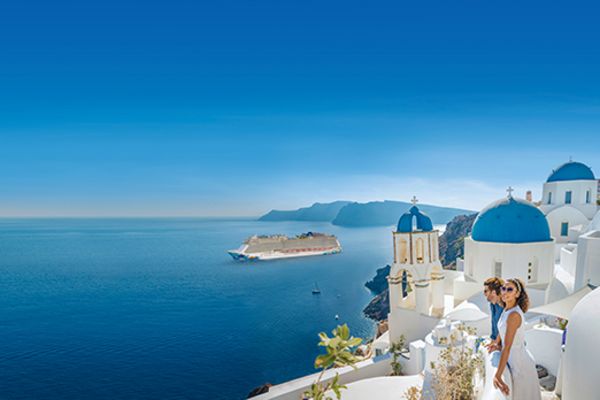 couple leaning over railing in greece looking out to sea