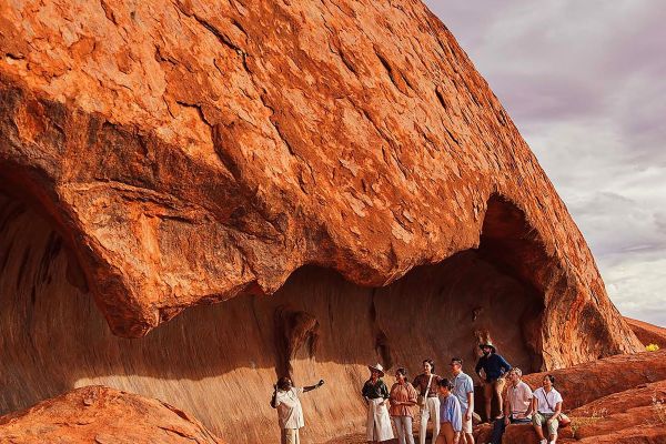 Tour guide leading people underneath large rocky overhang