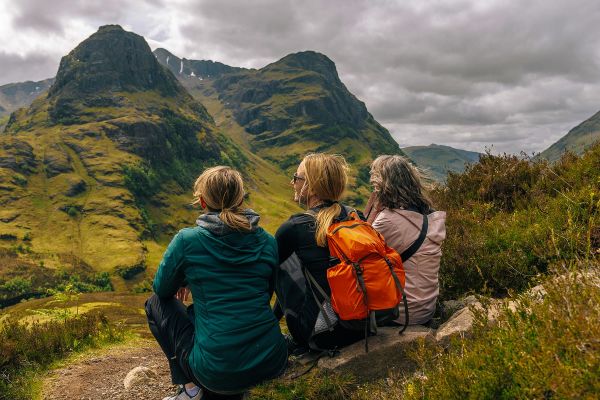 Three female hikers resting on a hill under a cloudy sky
