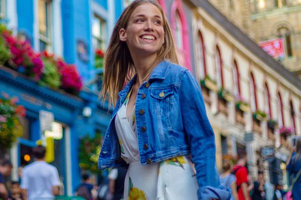 Young woman in a floral dress smiling on a colourful city street