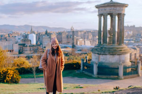 Woman in a long brown coat posing on Carlton Hill in Scotland
