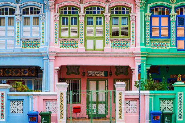 Woman posing in front of a white building with bright, multi-coloured window frames