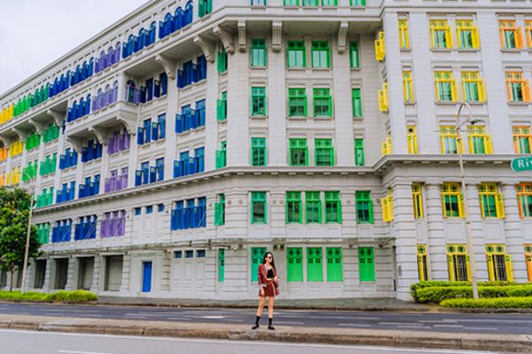 woman standing next to building with different coloured windows