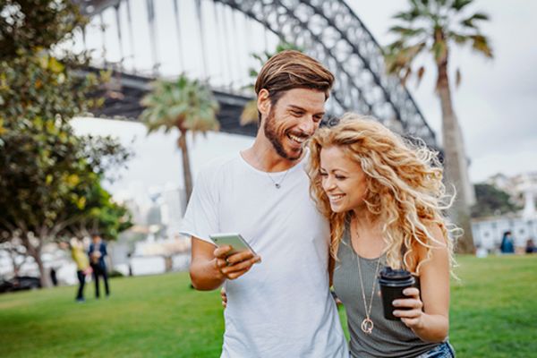 Couple walking arm in arm with the Sydney Harbour Bridge in the background