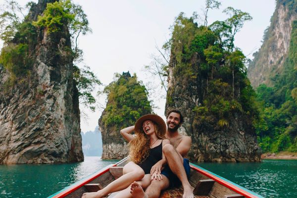 Couple relaxing on a boat sailing through large rocks in Thailand