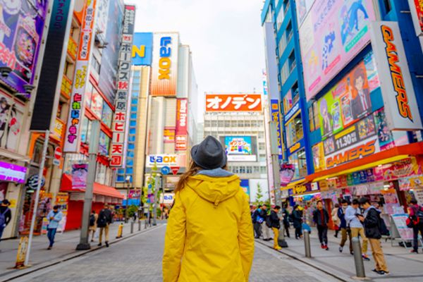 Person in a yellow coat standing in a busy street in Akihabara Japan