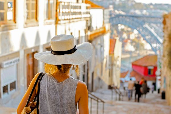 Woman in a large white hat, walking down cobblestone steps in Europe