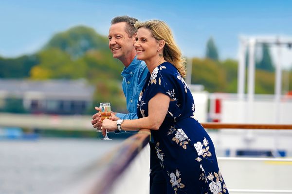 Couple on the edge of a cruise ship holding champagne
