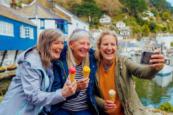 Three friends taking a selfie holding ice creams in a harbour town