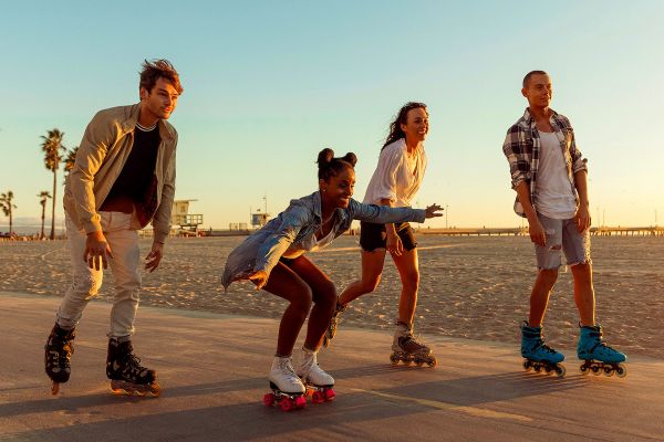 Young adults rollerblading on a thin road on a beach at sunset