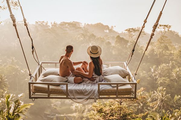Couple sitting on a swinging bed overlooking the jungle in Ubud