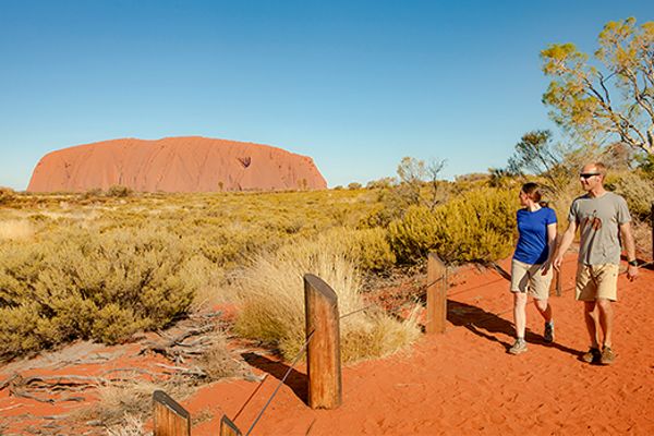 Couple walking past Uluru on a hot day