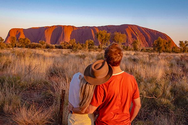 Couple embracing looking at Uluru in the late afternoon
