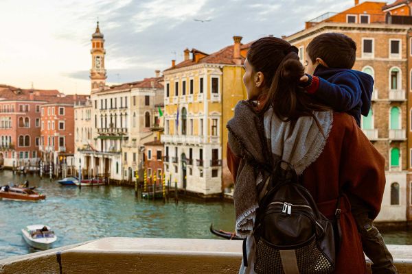 Mother and son looking over balcony at the buildings along a canal