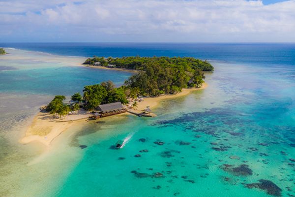 Small, heavily-forested tropical island with a single pier and clear ocean water