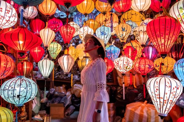Woman in a white dress surrounded by large hanging lanterns in Vietnam