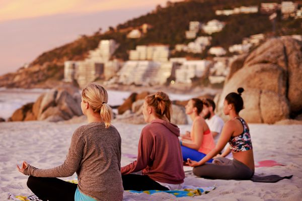 Women meditating on a beach in the late afternoon