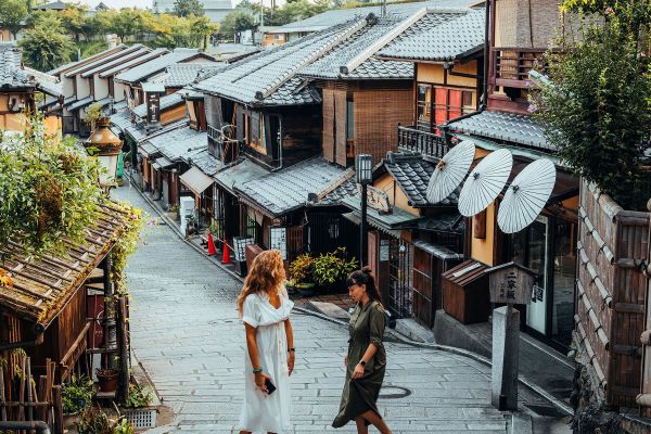 Two women walking along a quiet, Asian street